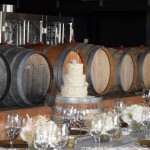 Wedding cake and centerpieces next to wine barrels