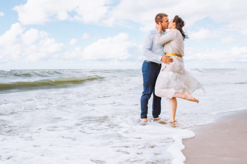 Young couple stand kiss while standing on the beach